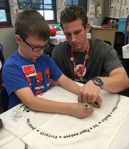 Volunteer and child work on pillowcase